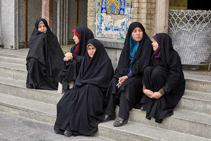 Zahra Rahnavard among women in black chadors sitting on stone steps