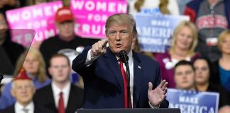 Trump Brands Senate Democrat a ‘FAKE DOCTOR’ Donald Trump speaking at a rally podium, pointing toward the audience