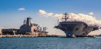 U.S. Sends THIRD Carrier Toward Iran War Aircraft carrier and support ships docked at a naval harbor