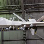 Ex-Google CEO Is Now Building ATTACK Drones military drone with missiles suspended in a hangar