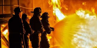 Firefighters battling a large blaze with a hose