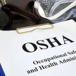 Workers Call Chinese-Owned Ohio Factory ‘UNBEARABLE’ OSHA document with safety goggles and respirator on desk