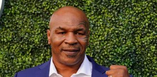 Mike Tyson in a blue suit raising a fist