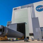 NASA Sends 12 Capsules to BURN Through Reentry Rocket stage moved on transporter outside large NASA assembly building