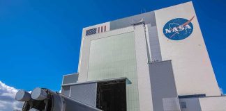 NASA Sends 12 Capsules to BURN Through Reentry Rocket stage moved on transporter outside large NASA assembly building