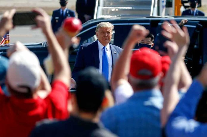Man in suit greeted by crowd with raised hands