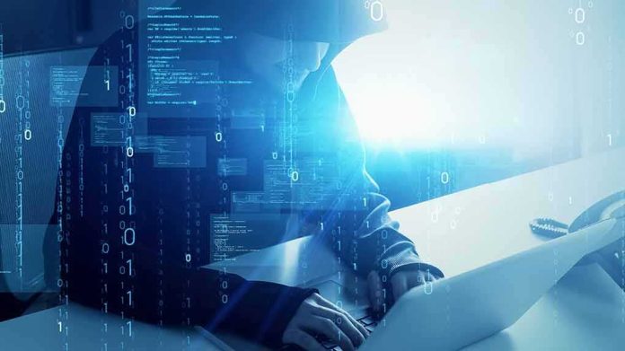 Hooded figure using a laptop with digital code overlay