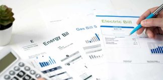 Record $1,500 Heating Bills STUNS Senate Race Hands reviewing utility bills with calculator and pen
