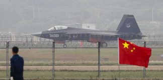 Why China Could OUTGUN Our F-35 Pilots Stealth fighter jet on runway behind fence with Chinese flag in foreground