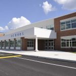 Hero Who Stopped School Shooter Now HAUNTED Modern school building with large windows and a clear sky