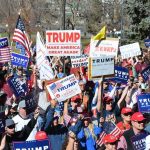 Rock Legend Opens Trump Rally Calling Himself ‘RADICAL’ Tim Teufel, Christian Jones, and Nash the Slash among a crowd at a political rally holding signs and flags